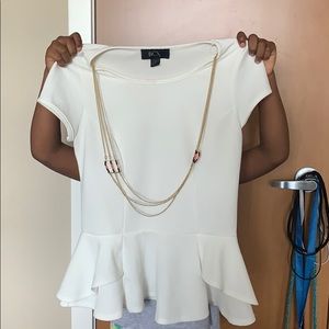 A white blouse with an attached gold necklace.